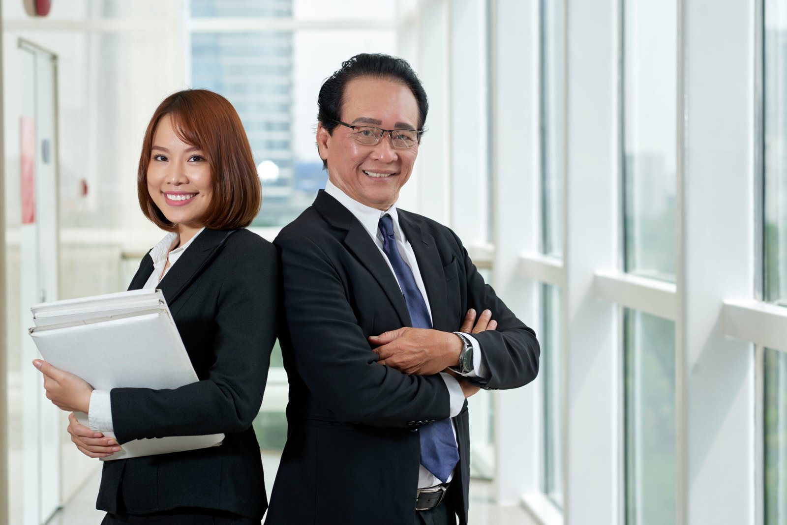 Smiling Asian business coworkers standing with their arms crossed